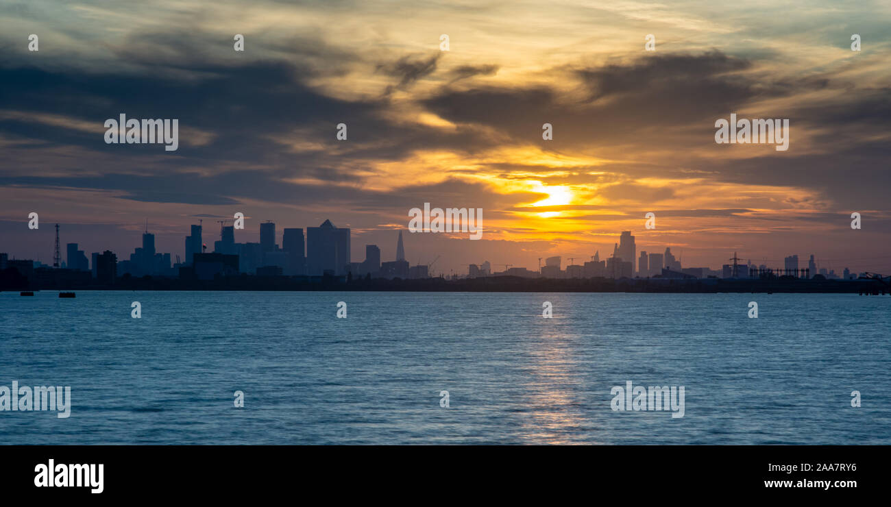 Die skylines von der Londoner City und den Docklands Canary Wharf Geschäftsviertel sind gegen die untergehende Sonne Silhouette wie vom Fluss Tham gesehen Stockfoto