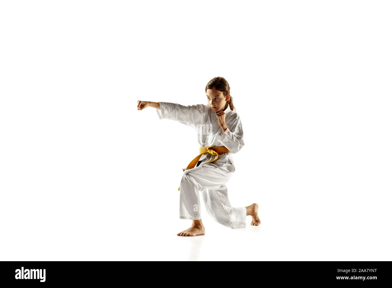 Zuversichtlich junior im Kimono üben Hand-auf-Hand zu bekämpfen, Kampfsportarten Junge Kämpferin mit gelben Gürtel s Ausbildung auf weißem Studiohintergrund. Konzept der gesunden Lebensstil, Sport, Action. Stockfoto