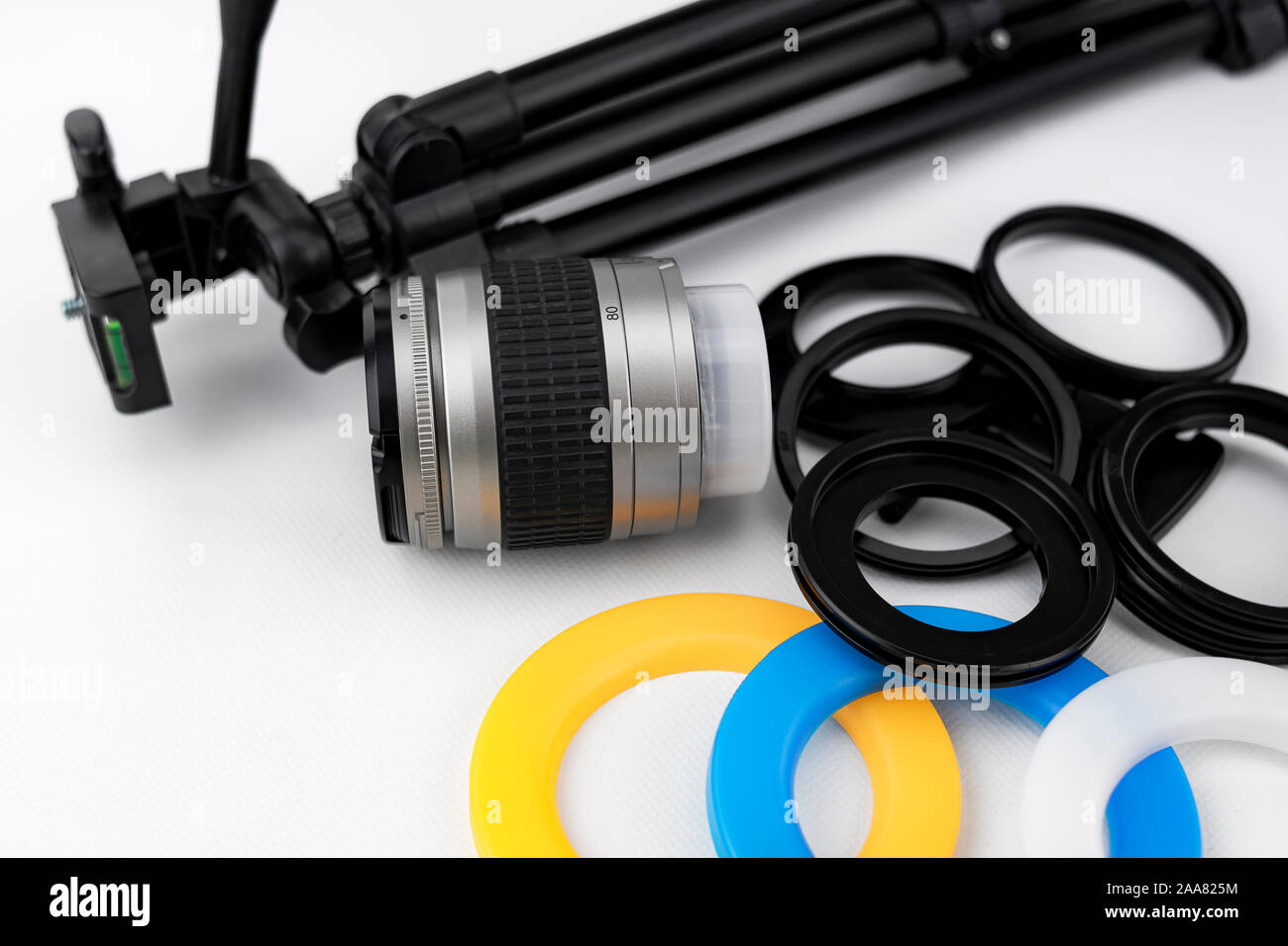 Objektiv für Fotoapparat, kleines Stativ und Adapter Ringe mit Farbfiltern für kreisförmige Flash Stockfoto