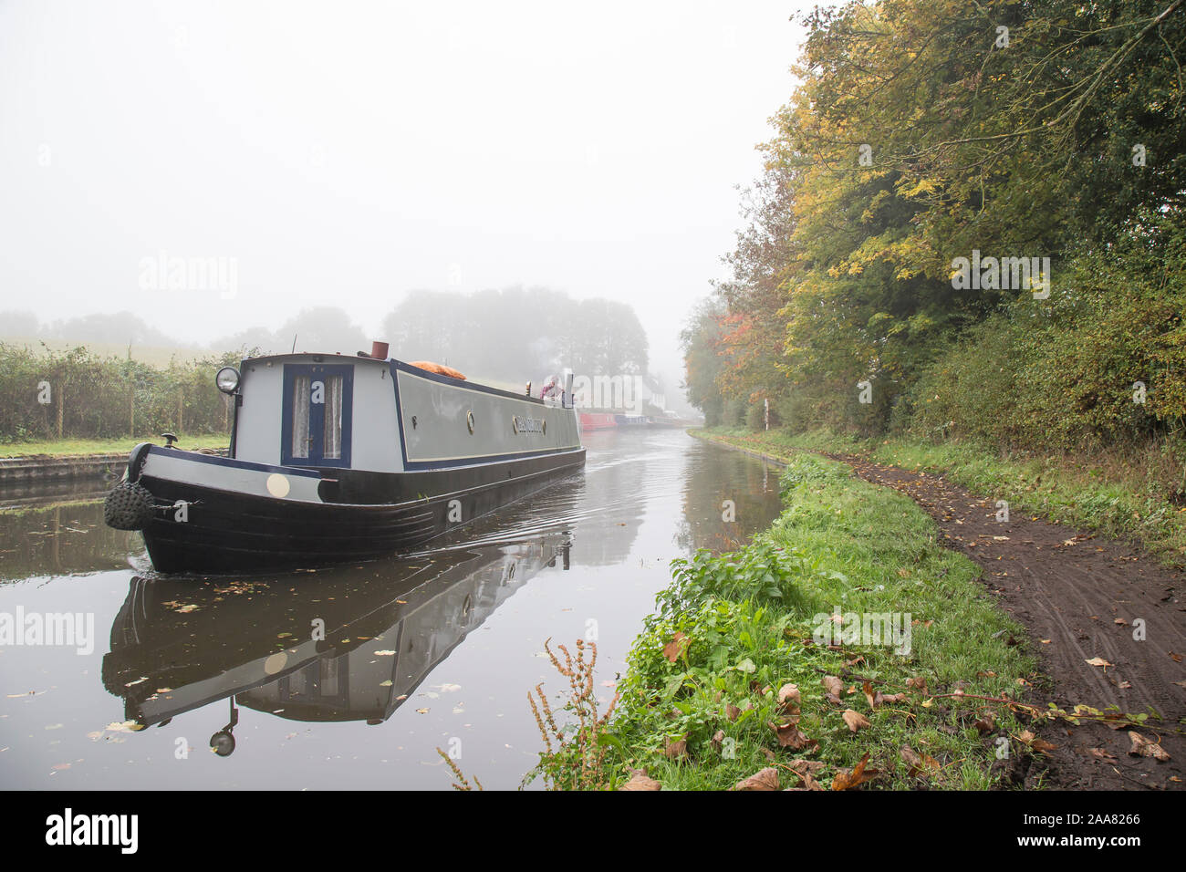 Nahaufnahme des isolierten britischen Kanalbootes im Morgennebel des Herbstes. Bootfahren auf britischen Kanälen, Narrowboat-Ferien. Stockfoto