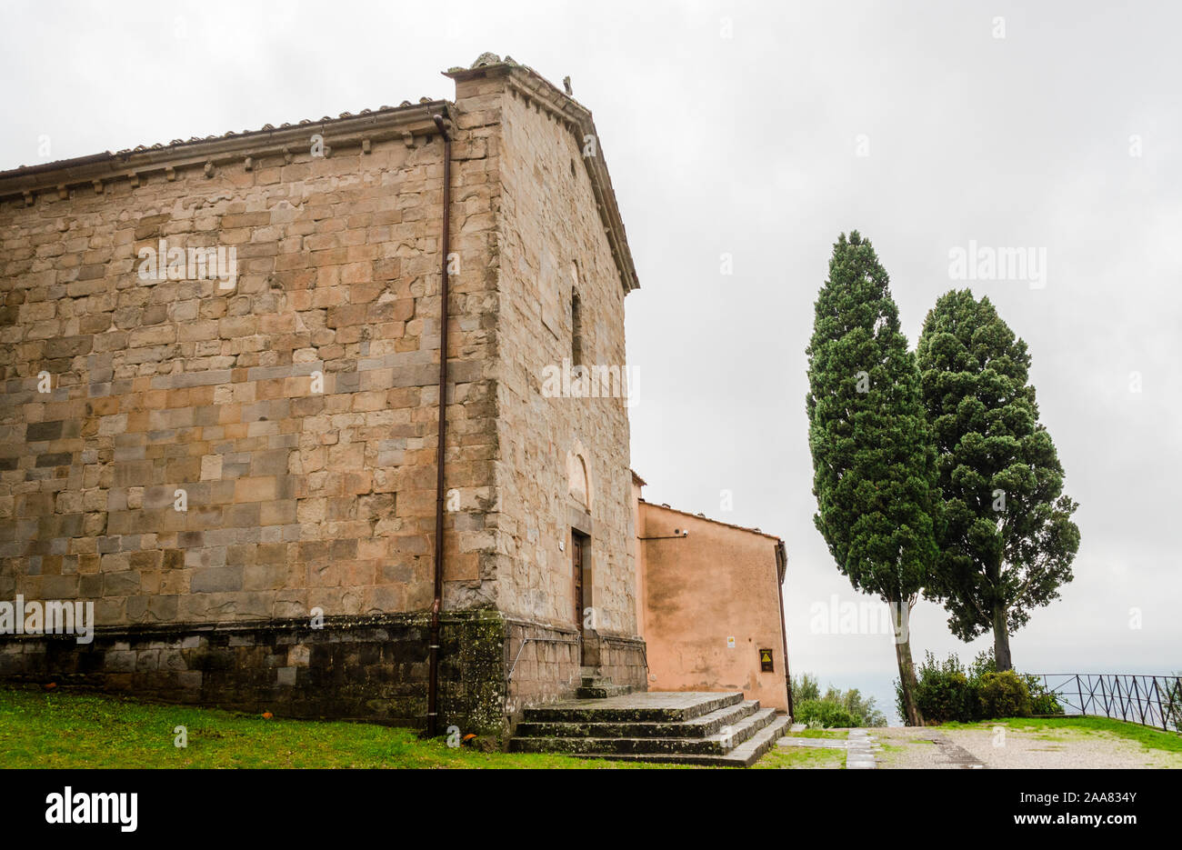 Mittelalterliche Pfarrkirche Fassade mit Zypressen in Italien Stockfoto