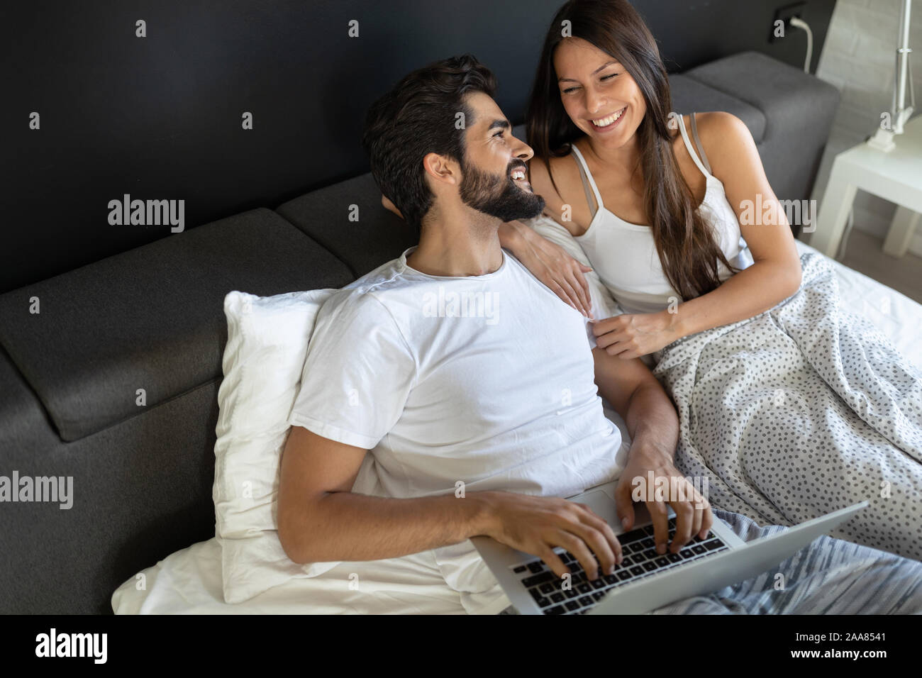 Glückliches Paar mit Laptop auf dem Bett im Schlafzimmer Stockfoto
