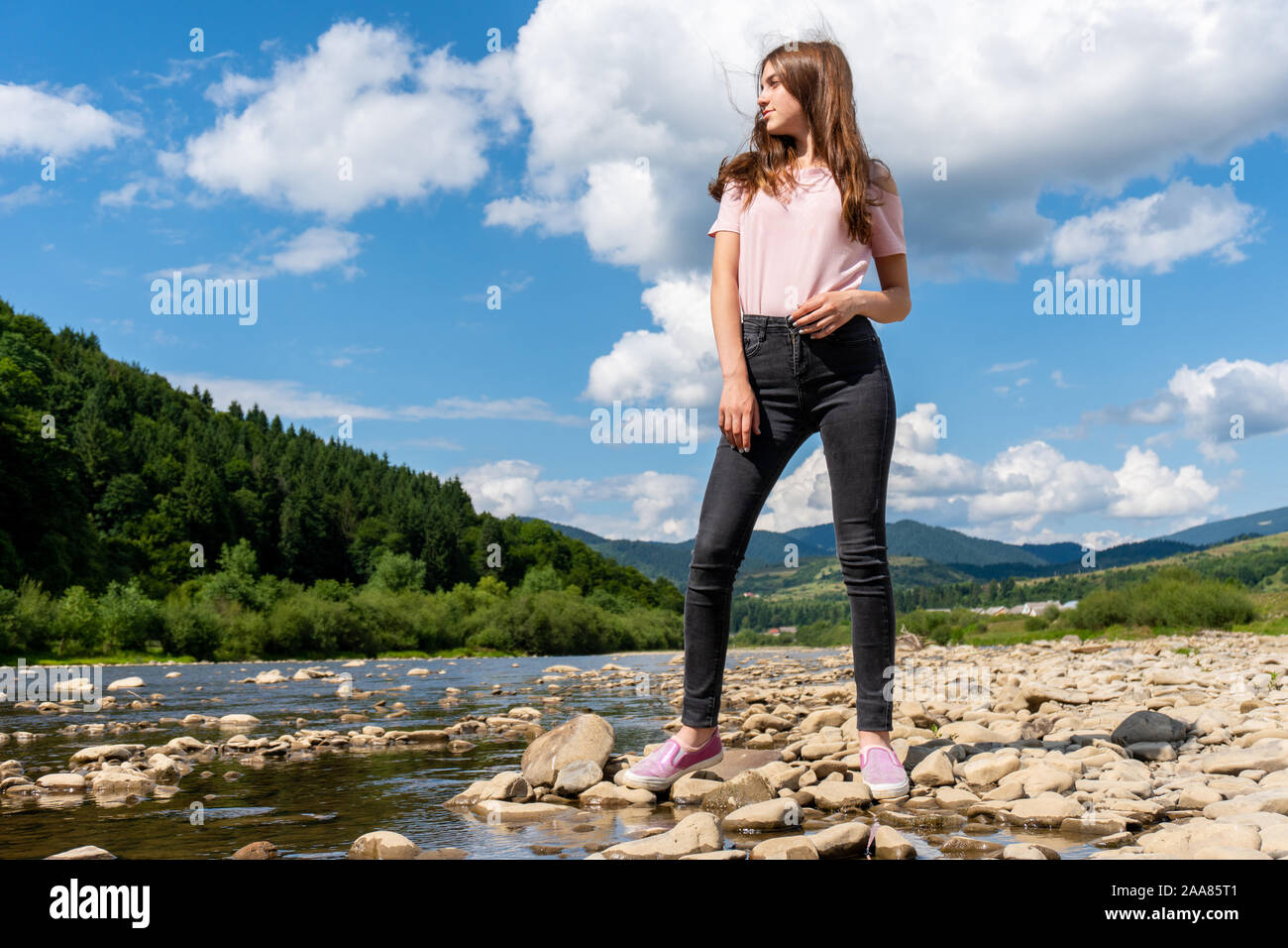 Teenager posing Girl steht auf Felsen in der Nähe von Mountain River Stockfoto