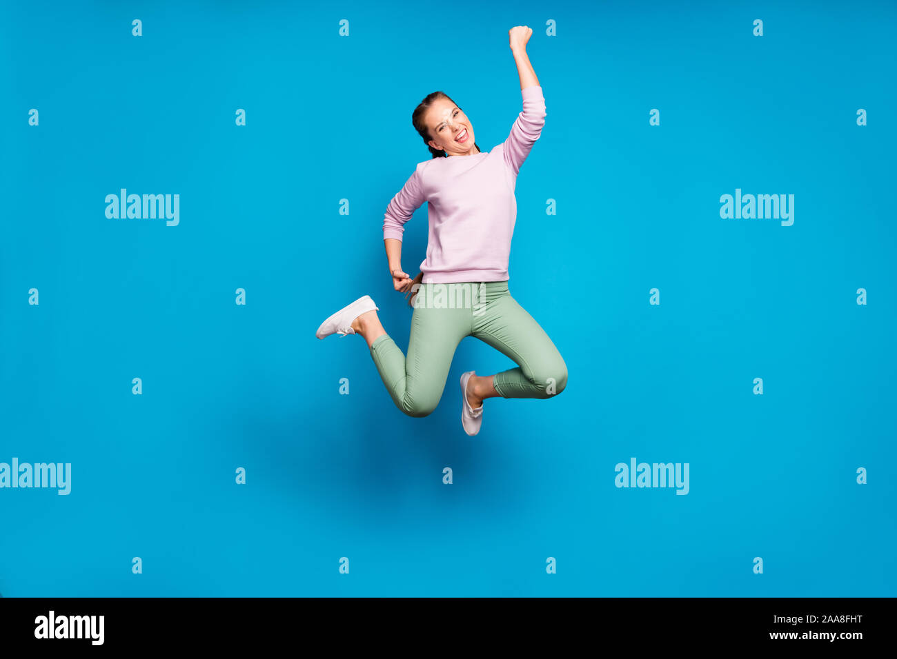 Volle Länge Foto ziemlich crazy Lady langen Zöpfen springen hoch Sport  Wettbewerb Meister tragen Casual rosa Pullover grüne Hose blau isoliert  Stockfotografie - Alamy