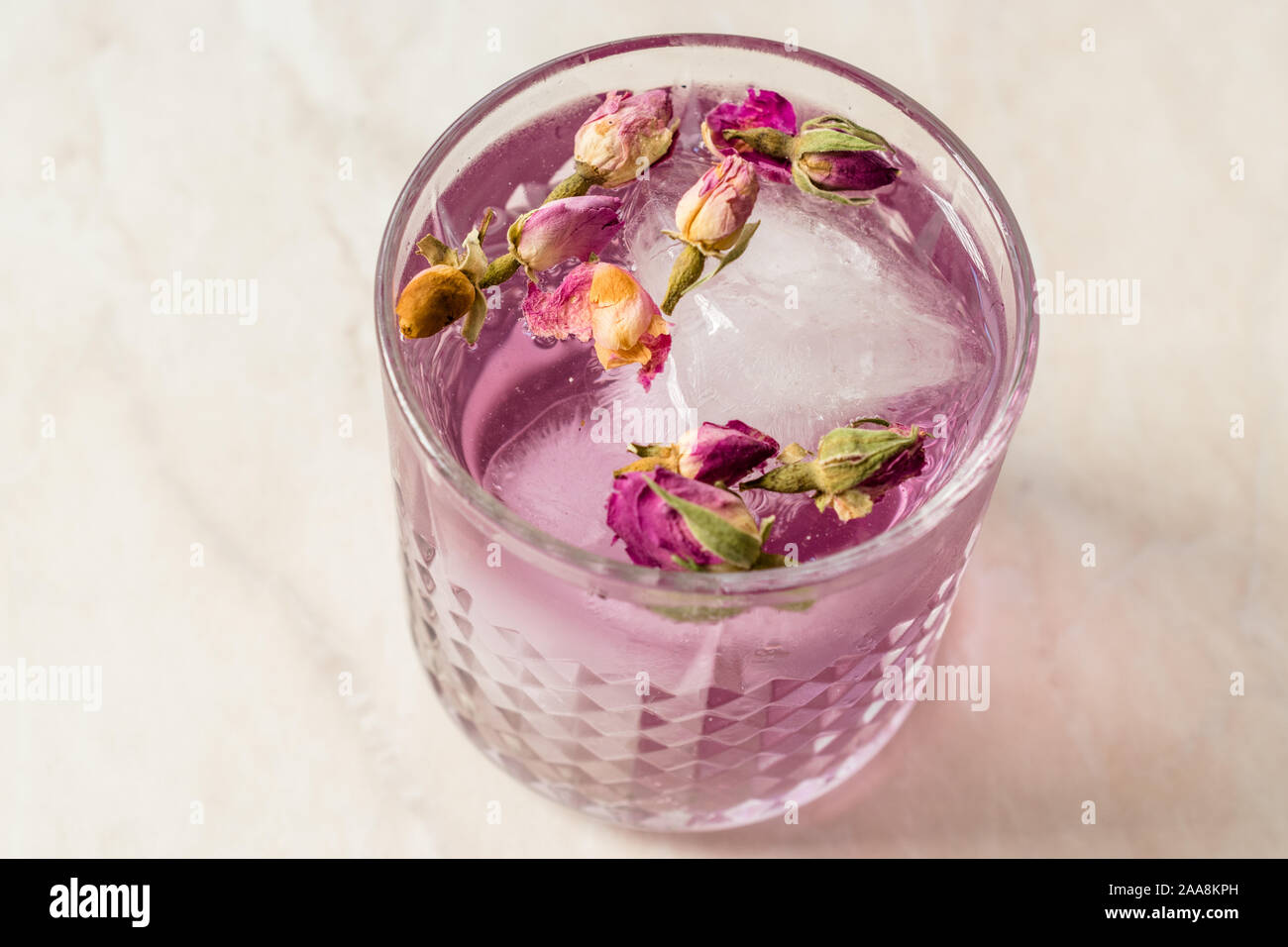 Pink Gin Tonic Cocktail mit Getrocknete Rosenknospen und Eis im Glas Schale. Bereit zu trinken. Stockfoto