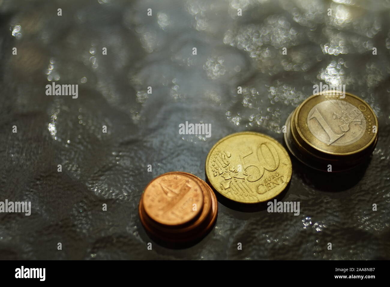 Stapel von glänzenden Münzen auf einem Glastisch Stockfoto