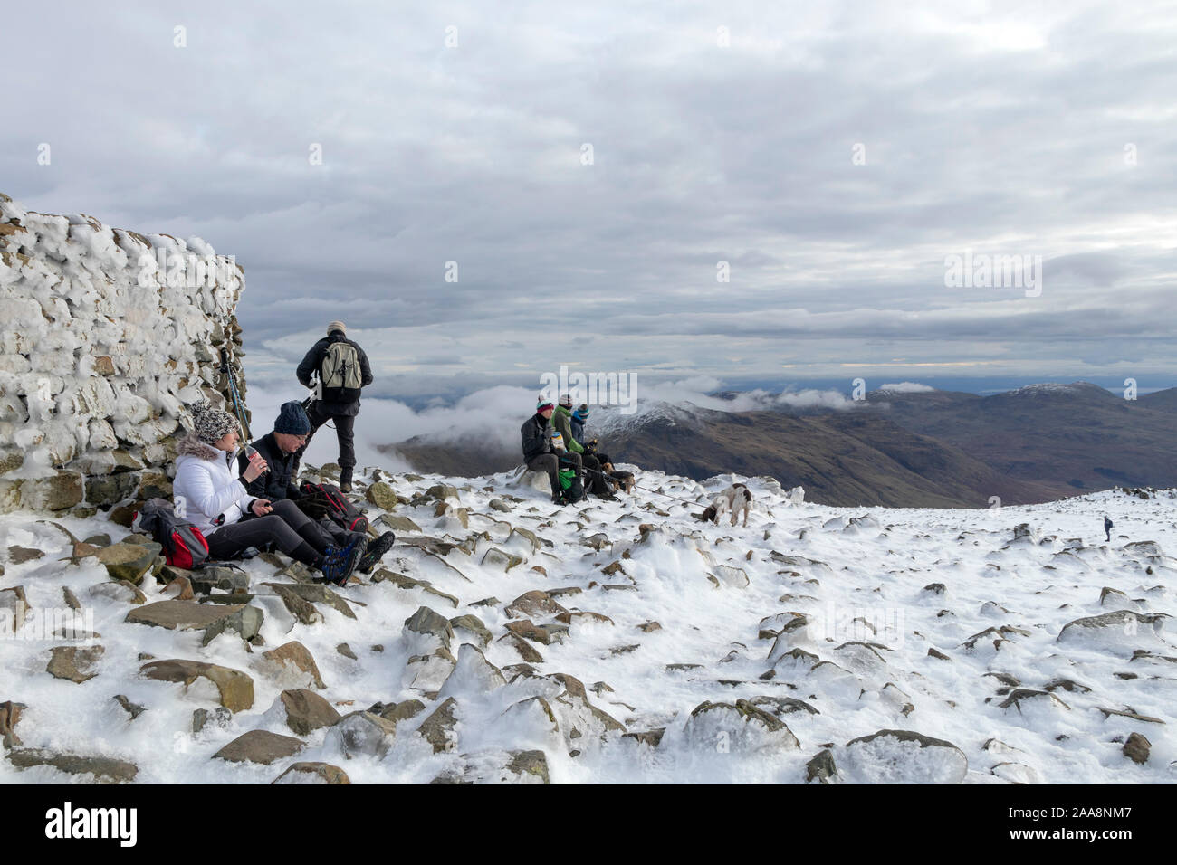 Wanderer genießen eine Pause auf dem Gipfel des Scafell Pike im Winter, See, Bezirk, Cumbria, Großbritannien Stockfoto