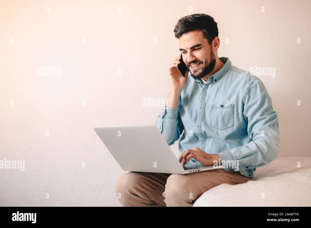 Glückliche Menschen sprechen über Smart Phone, während mit Laptop Computer zu Hause. Stockfoto
