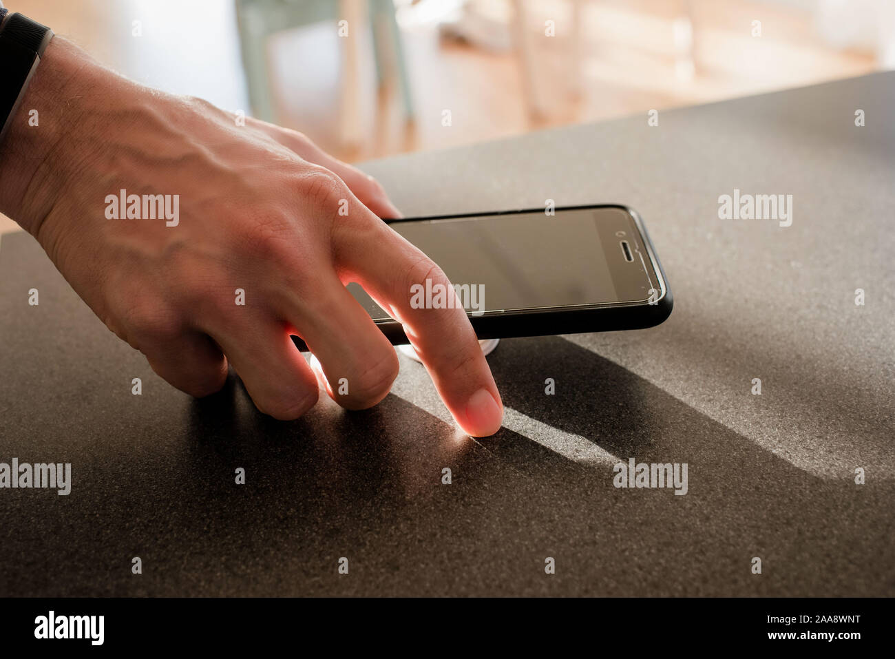 Mans hand mit einem Telefon in der Küche zu Hause. Stockfoto
