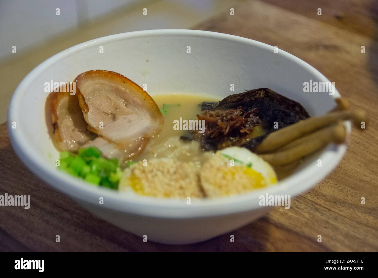 Eine Schüssel mit traditionellen Japanischen Schweinefleisch Ramen Suppe, mit enoki Pilze, mittlere gekochte Eier, Schalotten, Algen und Schweinefleisch Stockfoto