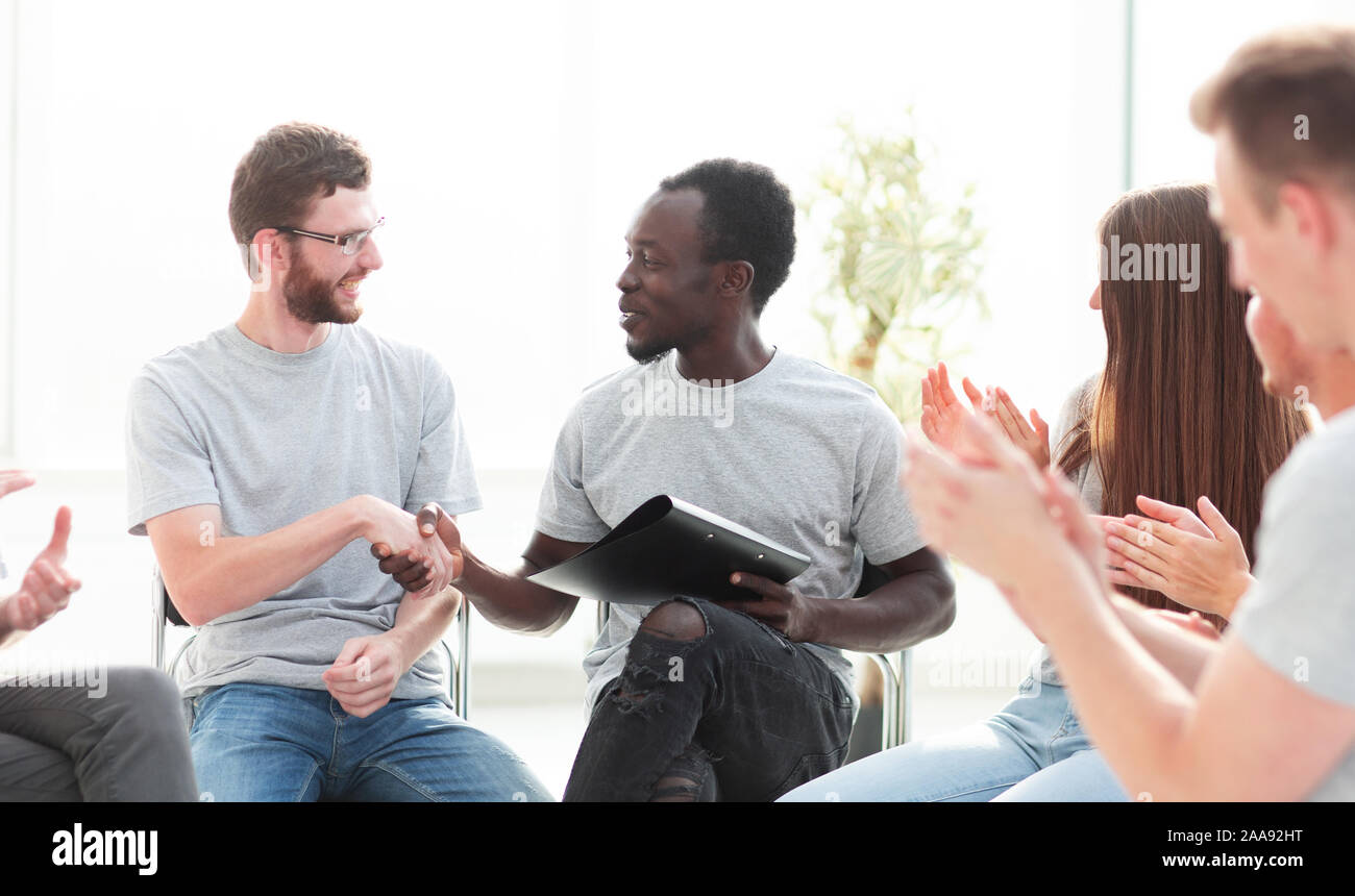 Junge Leute begrüßen sich unter dem Applaus ihrer Freunde. Stockfoto