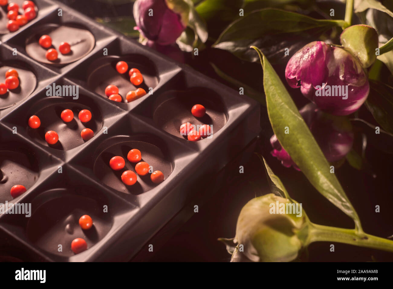 Bouquet von wunderschönen Blumen und Schokolade auf Holz- Oberfläche Stockfoto