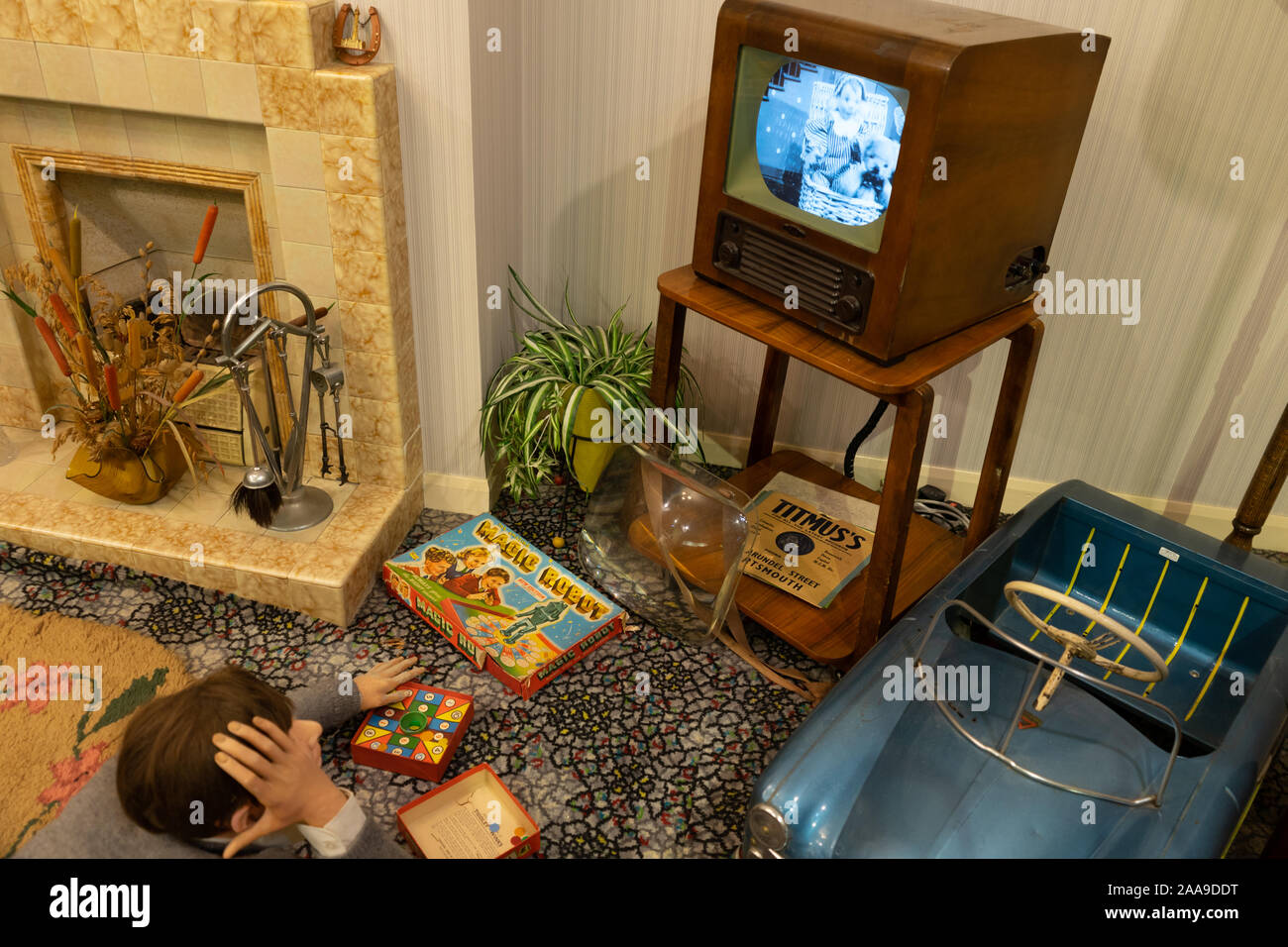 Ein Junge auf dem Boden beobachten einen alten Fernseher in den 60ern Wohnzimmer oder Lounge Stockfoto