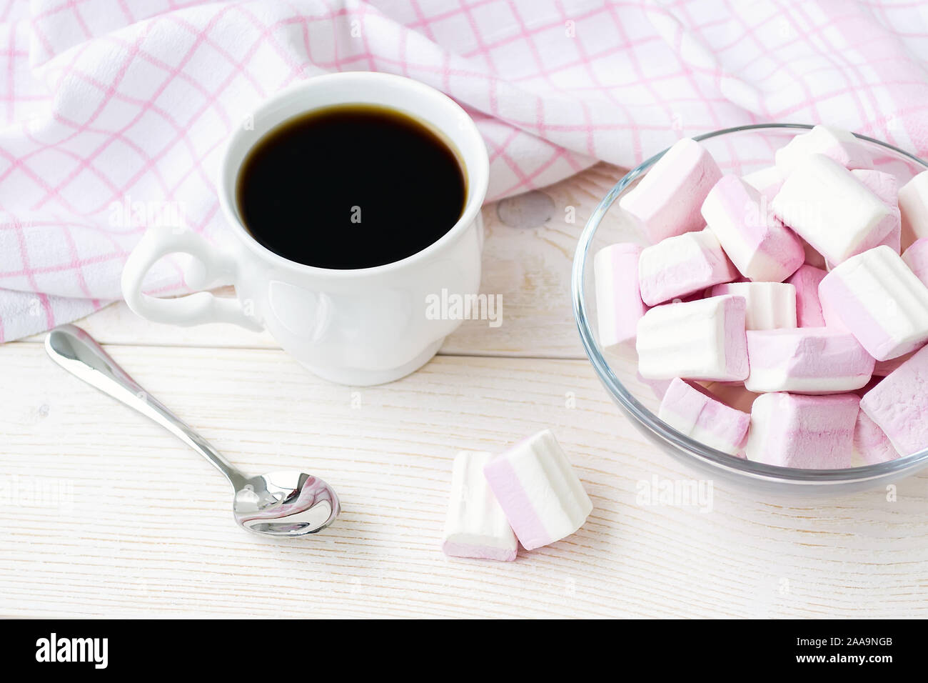 Tasse Kaffee und weiß rosa Flauschige Marshmallows in einem Glasgefäß auf hellem Holztisch. Süß und lecker Essen im Winter. Köstliche weiche Süßigkeiten. Ansicht von oben Stockfoto