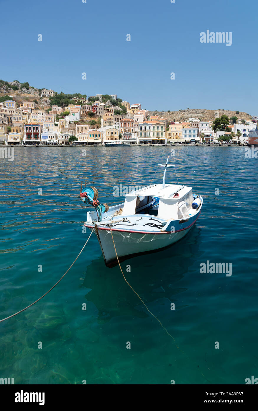Boot am Hafen von Simi Dodekanes Griechenland. Weiße Boot im Hafen Insel Symi mit bunten Gebäuden und blaues Meer Stockfoto