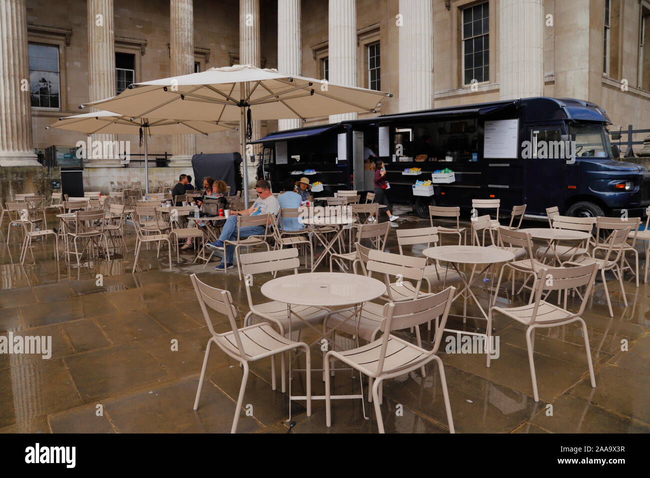 Die Leute sitzen unter einem Sonnenschirm an einem Café im freien Bereich  in der Nähe einer Nahrung Lkw im Britischen Museum in London, Vereinigtes  Königreich, an einem verregneten Sommer Stockfotografie - Alamy