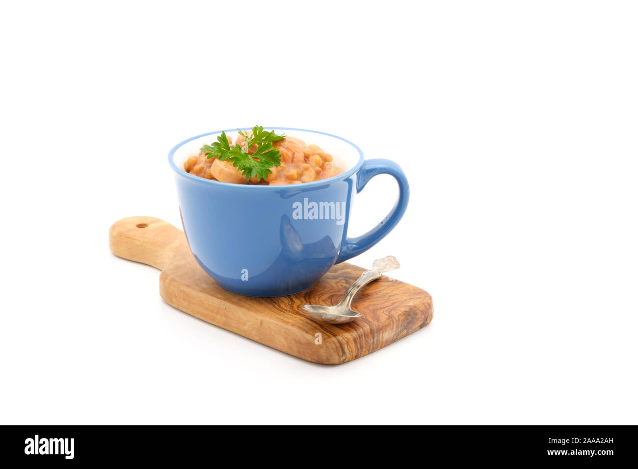 Blau Keramik Becher mit langsamen gebackene Bohnen und Weiners auf einem weißen Hintergrund. Stockfoto