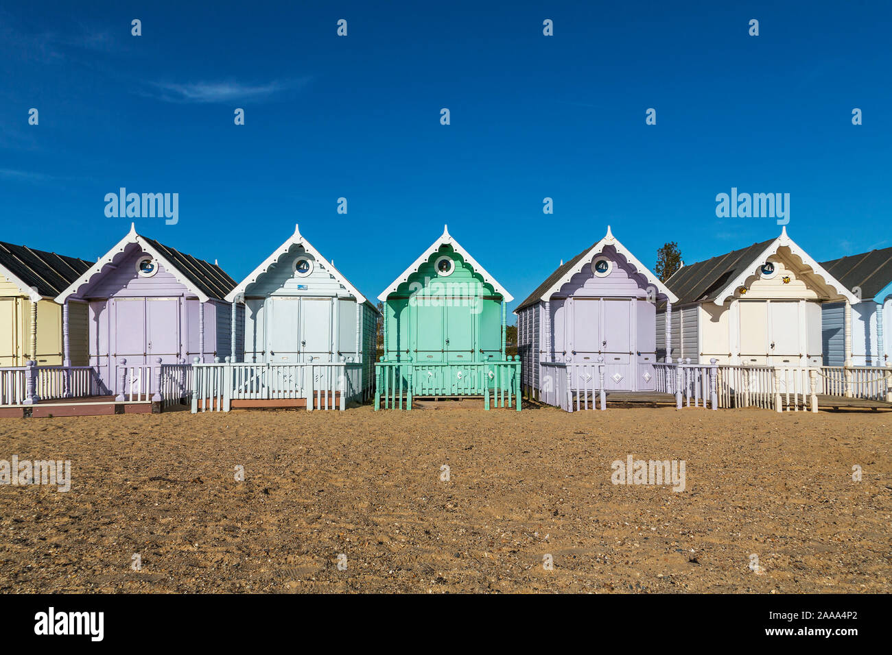 Eine Reihe von pastellfarbenen Holzhütten am West Mersea. Mersea Island, Essex, Vereinigtes Königreich. Stockfoto