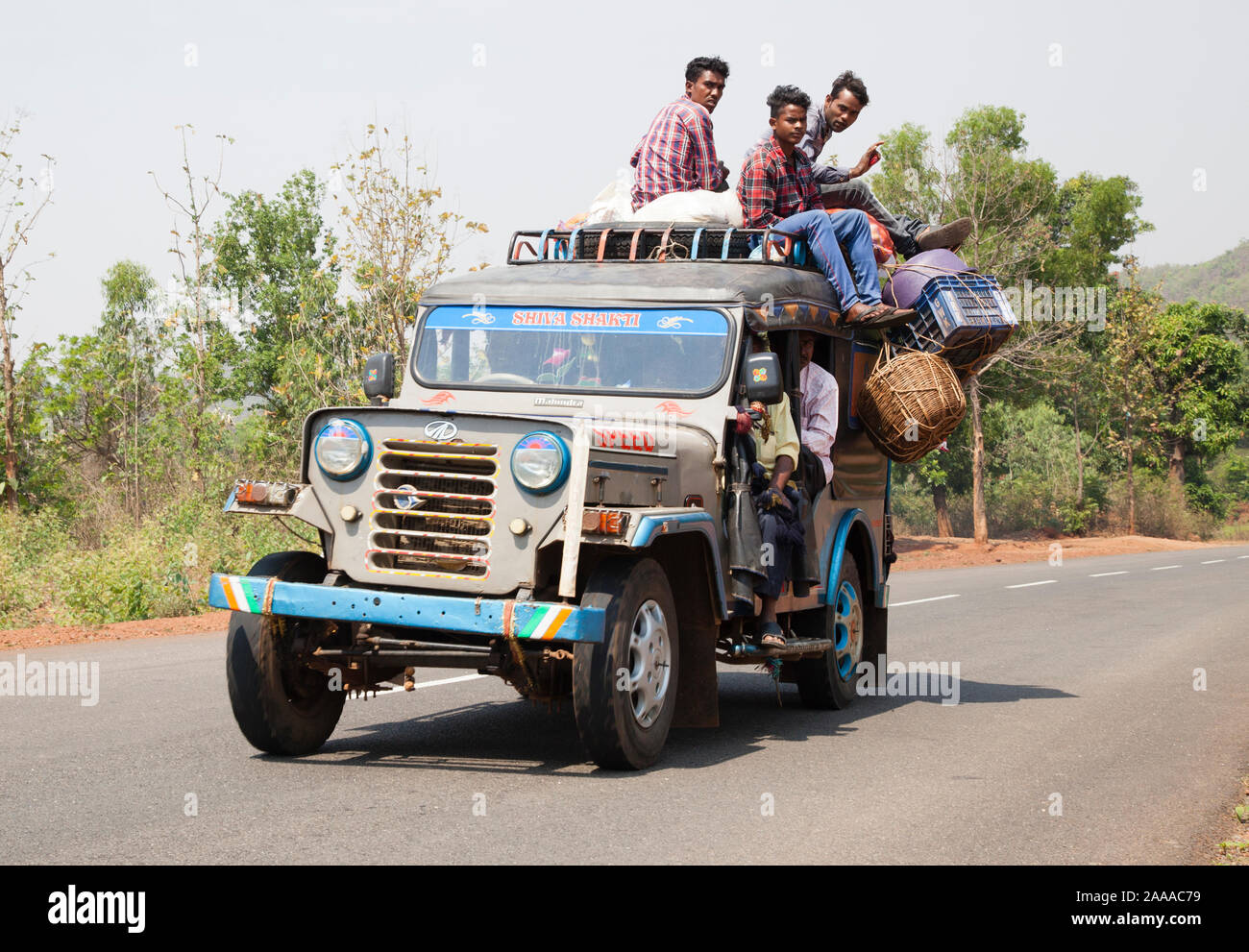 Passagiere klammern sich an überlastet Indischen Mahindra Jeep taxi ländlichen Odisha Autobahn Stockfoto