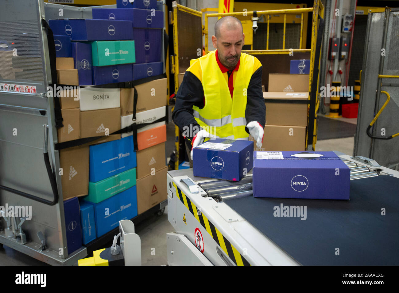 Mitarbeiter pack Pakete in Rollcontainer, Innenansicht des Paketzentrums, Pakete auf dem Förderband, Sortieren, Überblick über die Pakete, Förderbänder, die Inbetriebnahme der neuen mega Paketzentrum der Deutschen Post DHL in Bochum, 18.11.2019. | Verwendung weltweit Stockfoto