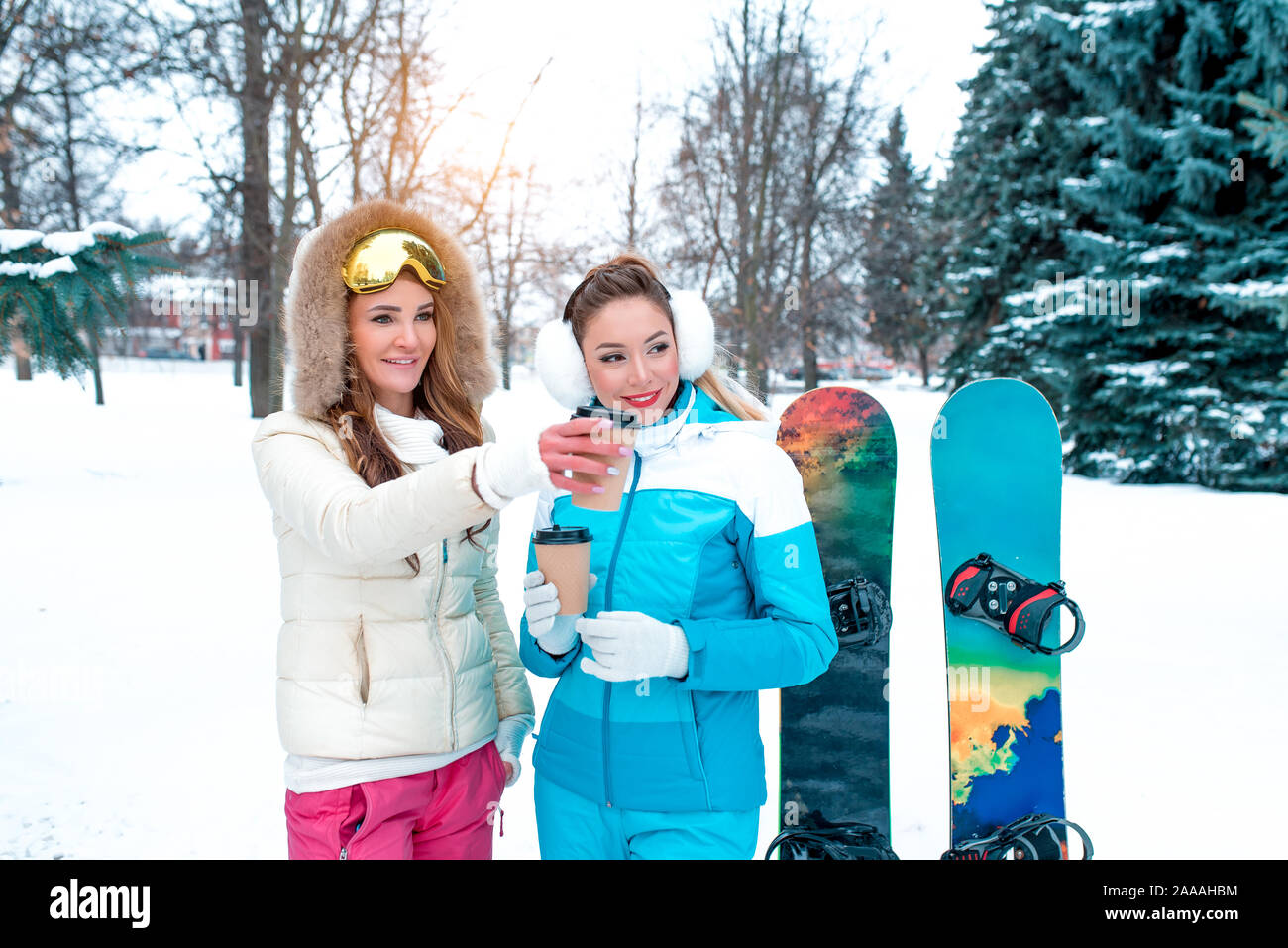 Zwei Mädchen Freundinnen Winter am Hang Resort, haben Rest Hände Gläser mit heißem Kaffee trinken Tee, glücklich lächelnde, kostenloses Open Space, snowboard Boards Stockfoto