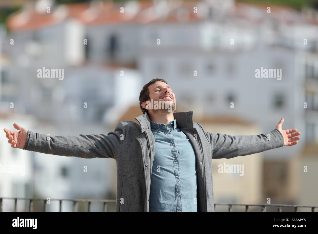 Glückliche Menschen tragen Jacke feiert der neue Tag stretching Arms im Winter in einer ländlichen Stadt Stockfoto