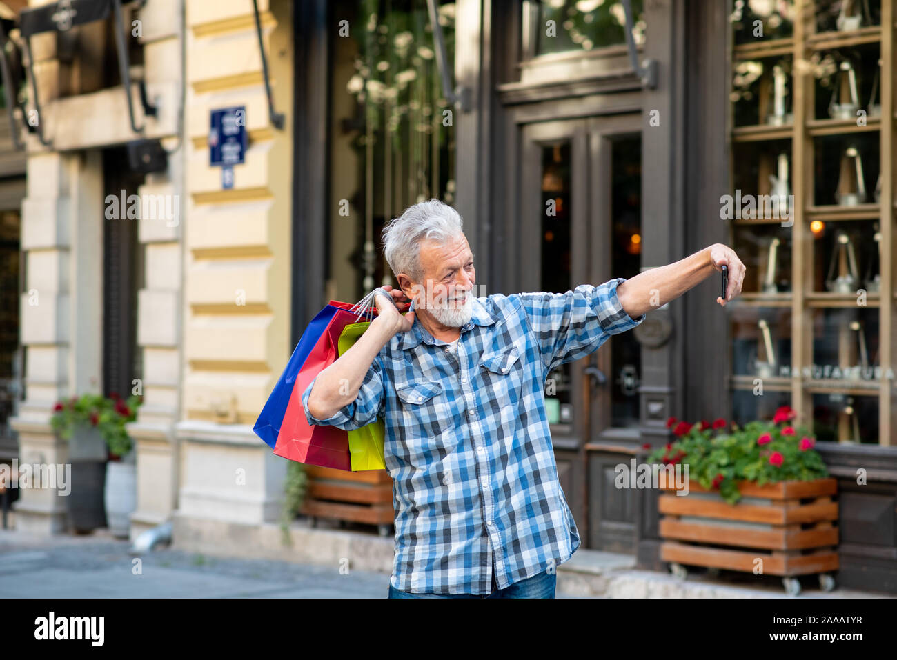 Fröhlicher älterer Mann unter selfie Holding Shopping Taschen Stockfoto