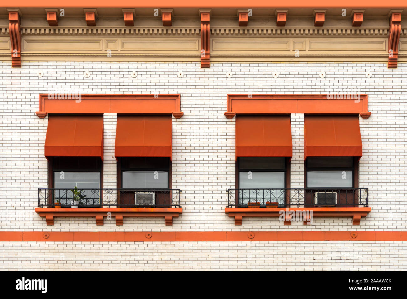 Orange Fenster Markisen auf ein weißes Ziegelgebäude Stockfoto