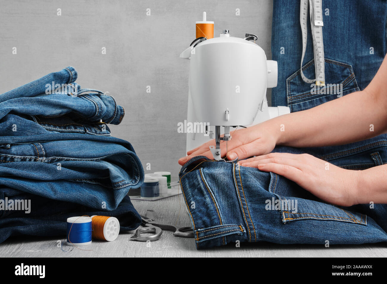 Nähen Jeans auf der Nähmaschine in der Werkstatt. Jeans reparieren. Stockfoto