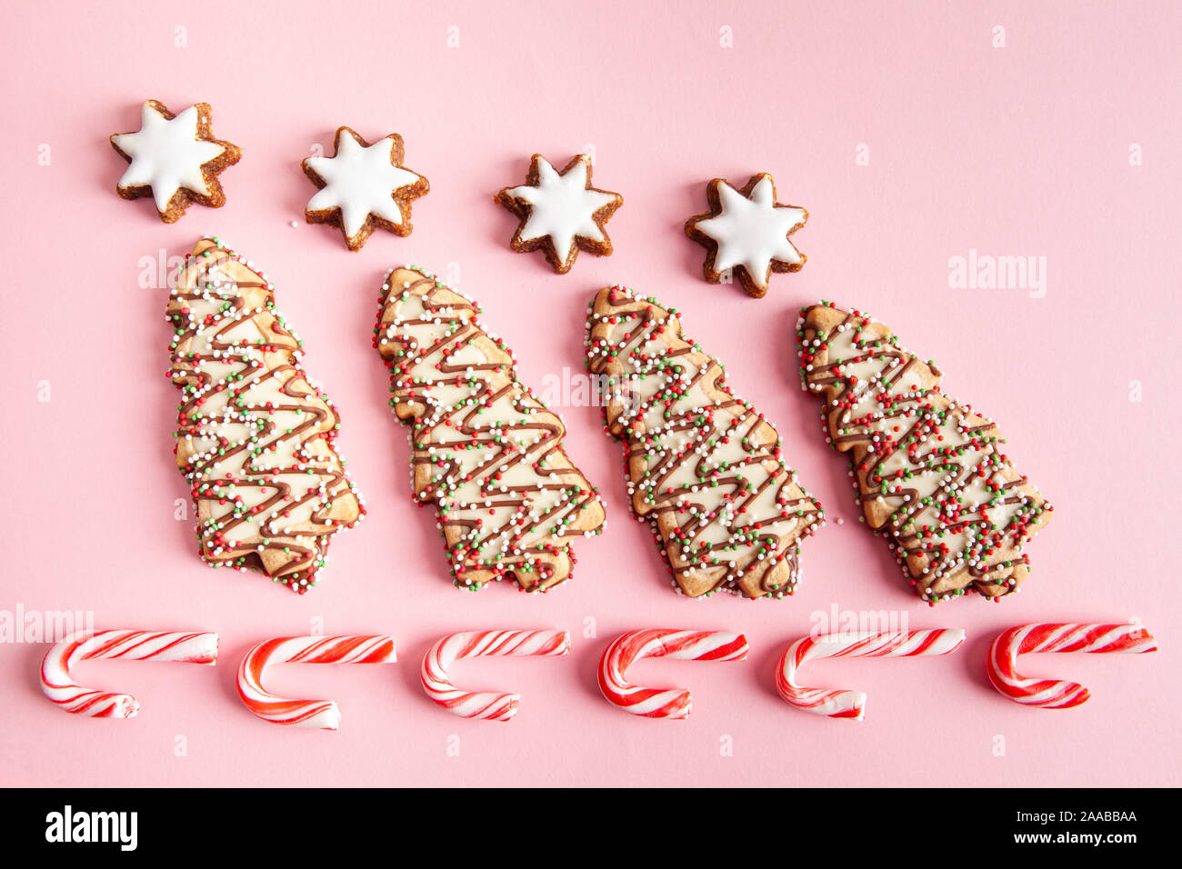 Weihnachten süße Nahrungsmittel - Weihnachtsbaum Kekse mit Zuckerstangen auf rosa Hintergrund angeordnet Stockfoto