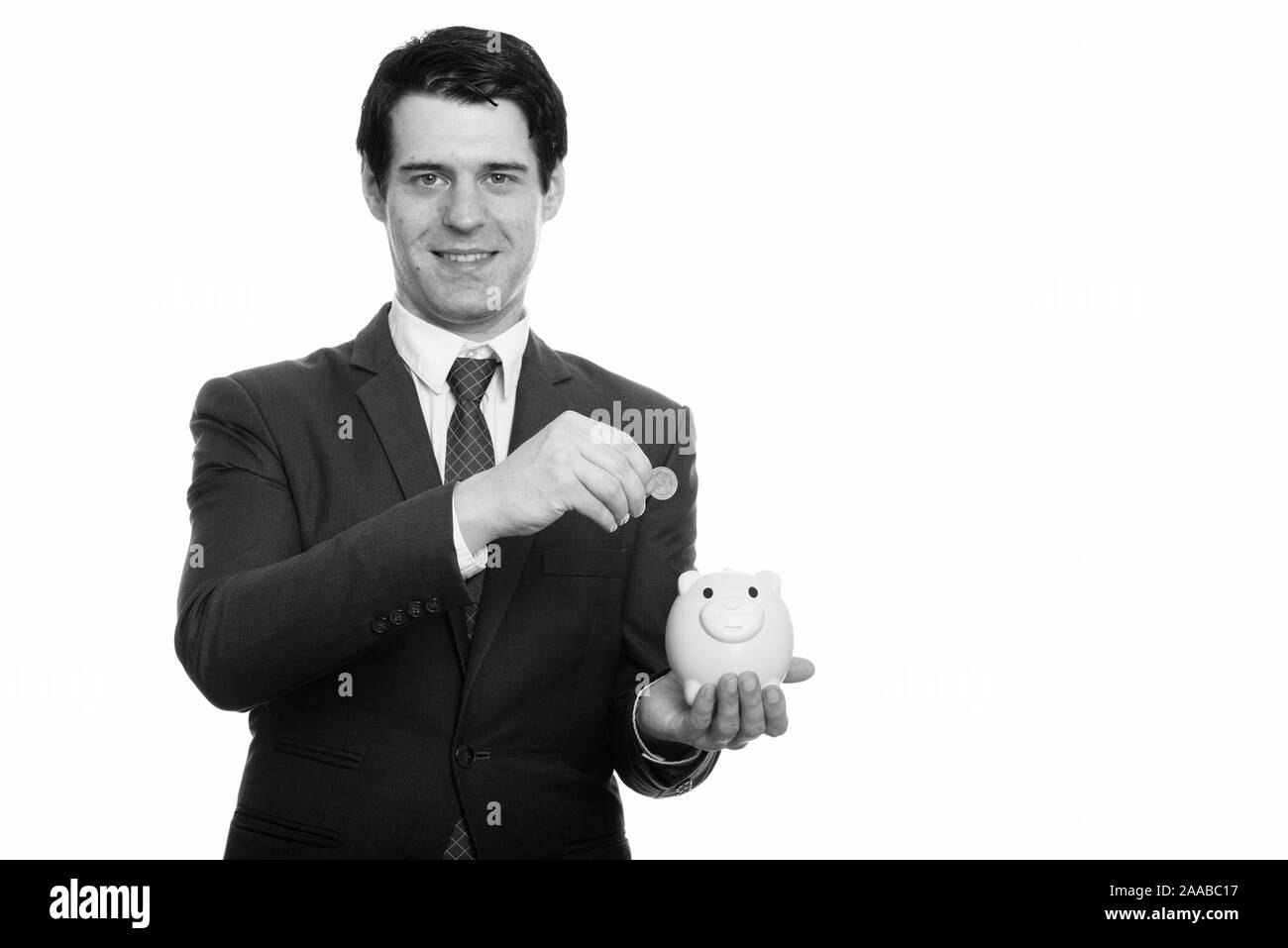 Studio geschossen von glücklich, Geschäftsmann, Lächeln, während sie Münze in piggy Bank Stockfoto