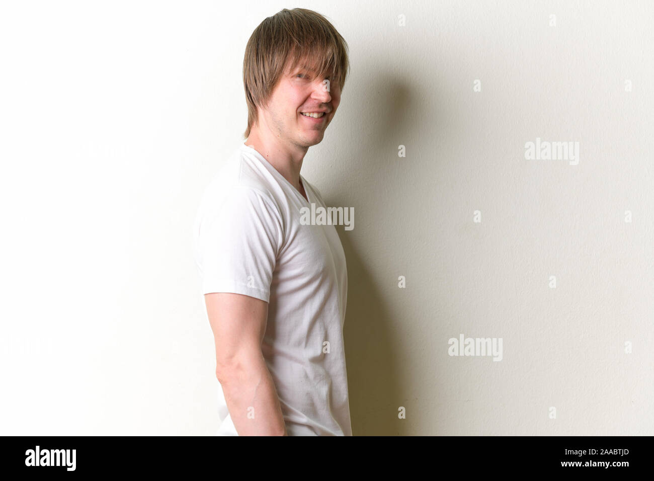 Profil anzeigen von glücklichen jungen Mann mit langen Haaren an Kamera suchen Stockfoto