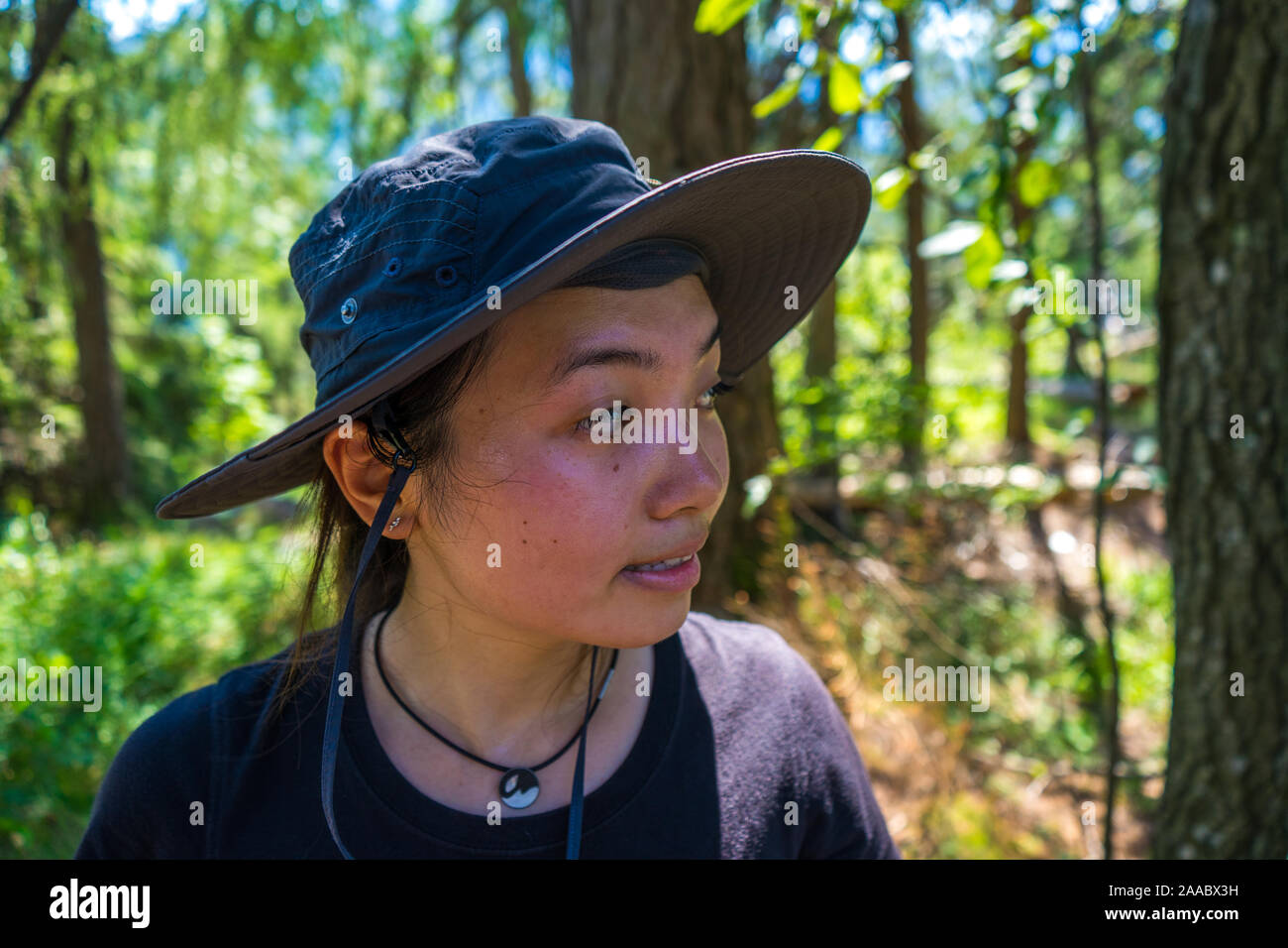 Junge weibliche asiatische Modell mit einem Hut in den Wäldern, im Hintergrund, blaue Wasser, See Angelegenheit, Österreich Stockfoto