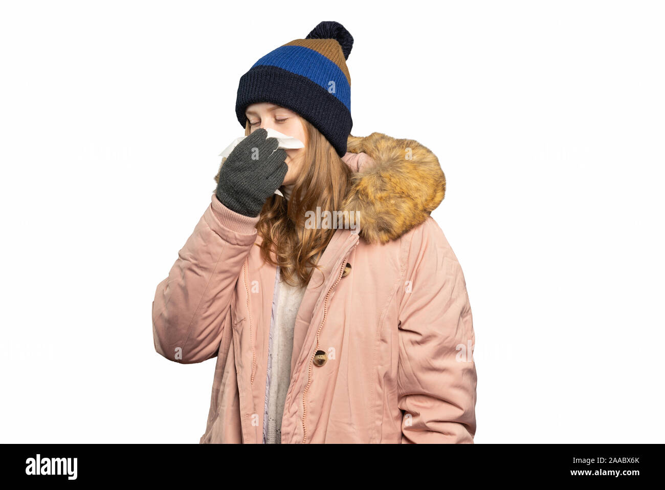 Eine junge Frau im Winter Kleidung hält ein Taschentuch und Schlag die Nase Stockfoto
