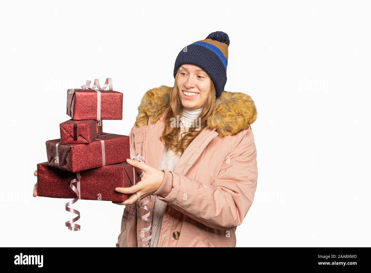 Junge Frau in Winterkleidung mit einem Stapel Weihnachtsgeschenke Stockfoto