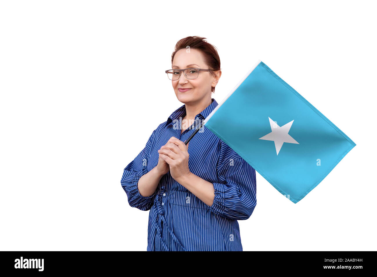 Somalia Flagge. Frau mit Flagge. Schönes Portrait der Dame im mittleren Alter 40 50 Jahre alt, eine große Flagge mit weissem Hintergrund. Stockfoto