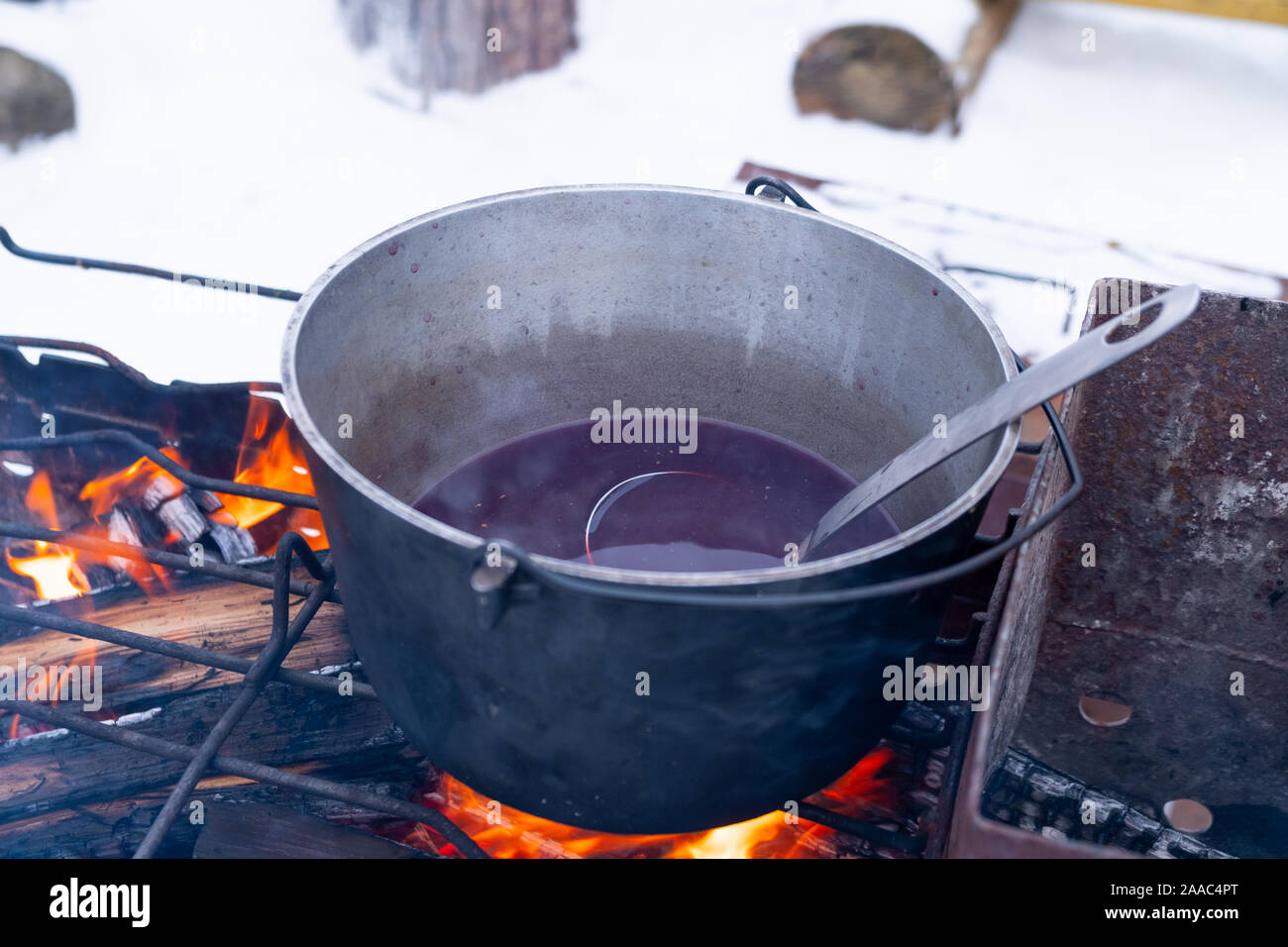 Bei einem Feuer in einem Topf Vorbereitung Glühwein. Hot rot Wein am offenen Feuer im Winter Stockfoto