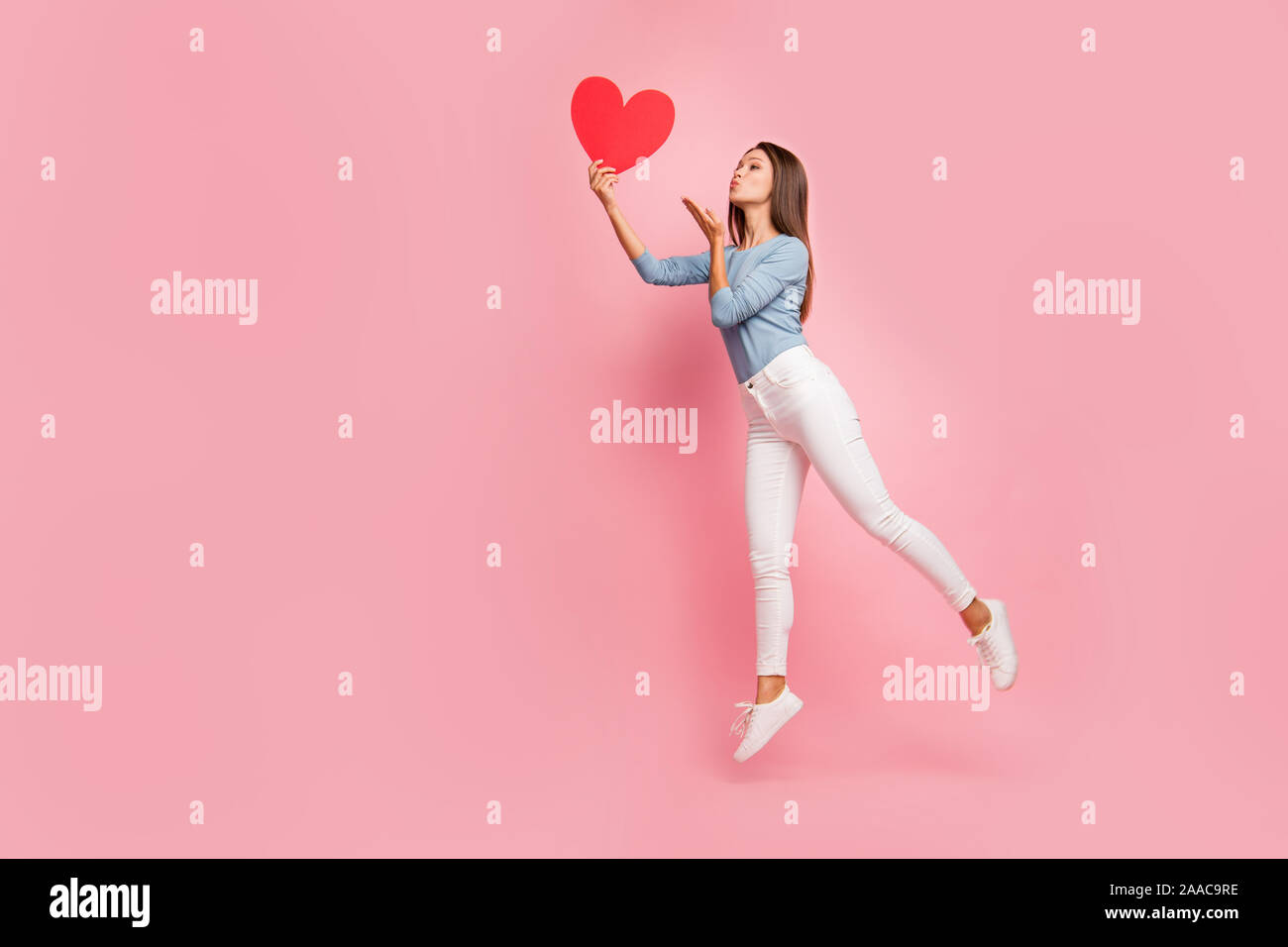 Volle Länge Körpergröße Seite braunhaarige Profil Foto fröhliche, positive niedlich Hübsche zarte Mädchen senden Luft küssen zu Herzen statt isolierter Pastell Stockfoto