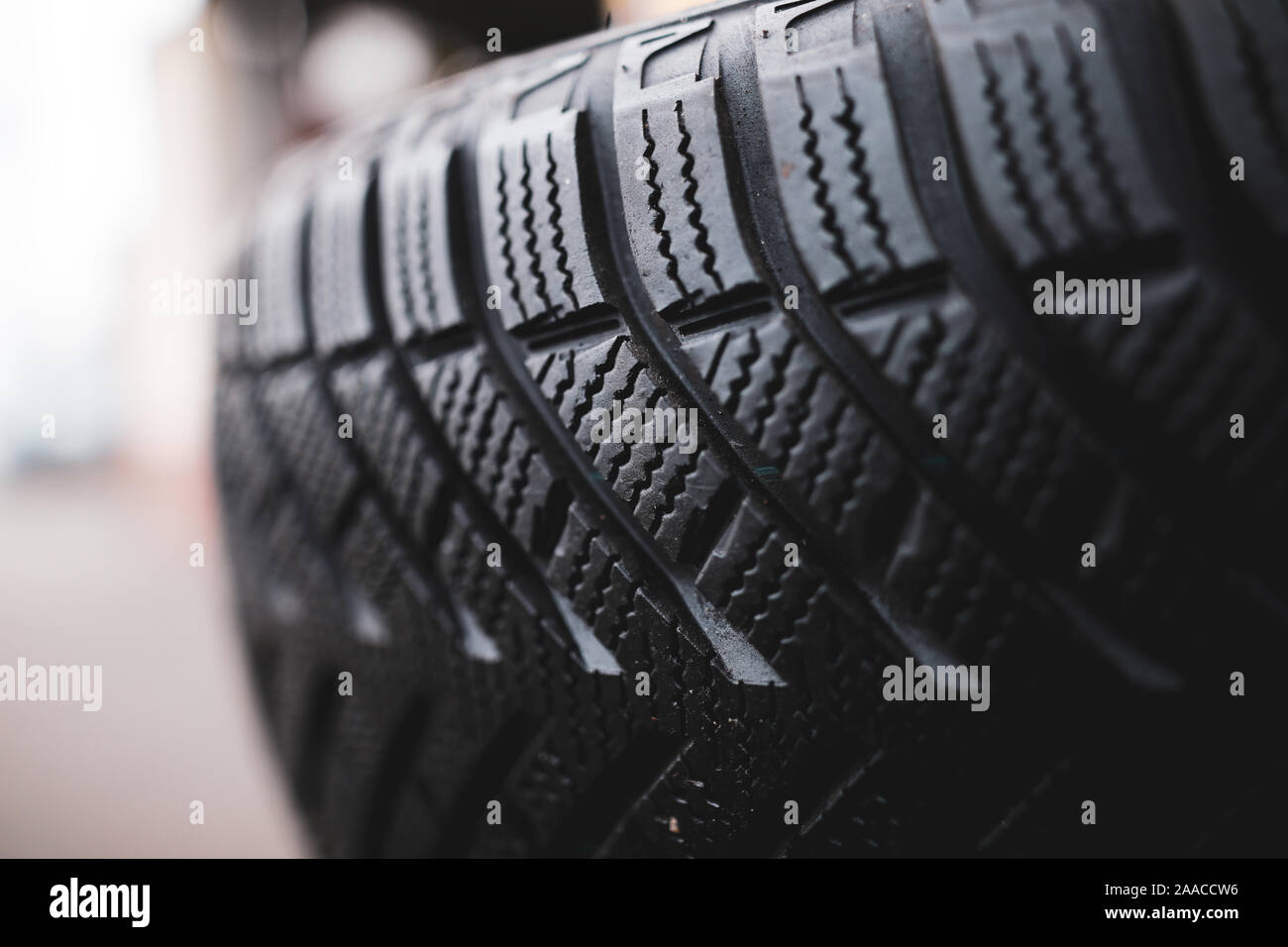 Flache Tiefenschärfe (selektive Fokus) Bild mit Details eines schmutzigen Winterreifen in einer KFZ-Werkstatt. Sipes und Schnitte in der Lauffläche hervorgehoben. Stockfoto