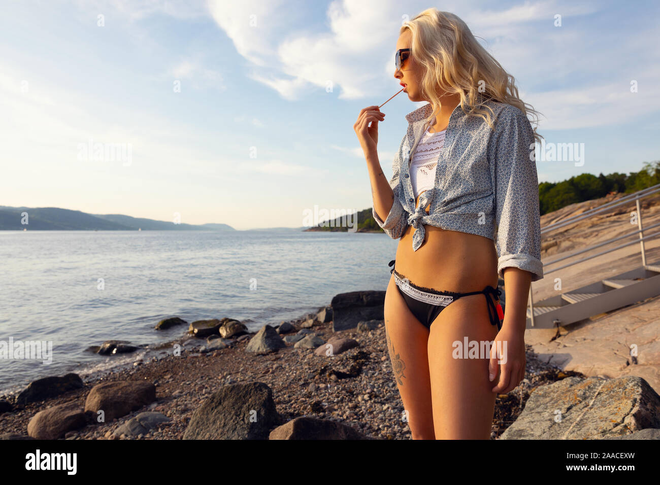 Schöne junge Frau Essen gewürzt Eis am Strand Stockfoto