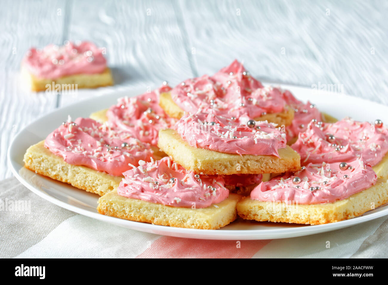 Köstlich süßen Shortbread Cookies mit Strawberry vanilla buttercream frosting auf einer weißen Platte auf einem Holztisch, Ansicht von oben, close-up Stockfoto