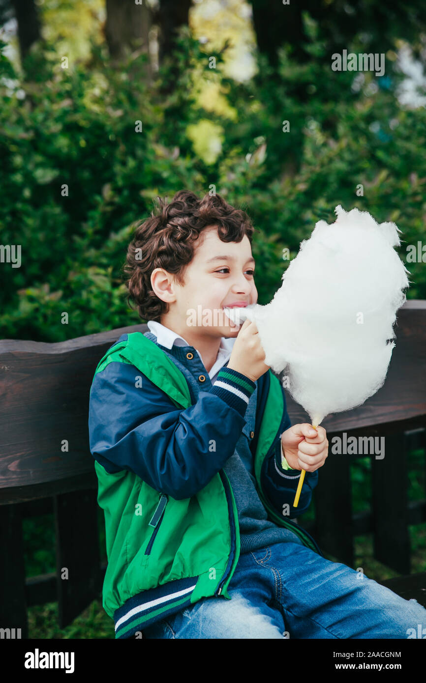 Happy little boy Essen Zuckerwatte in Park Stockfoto