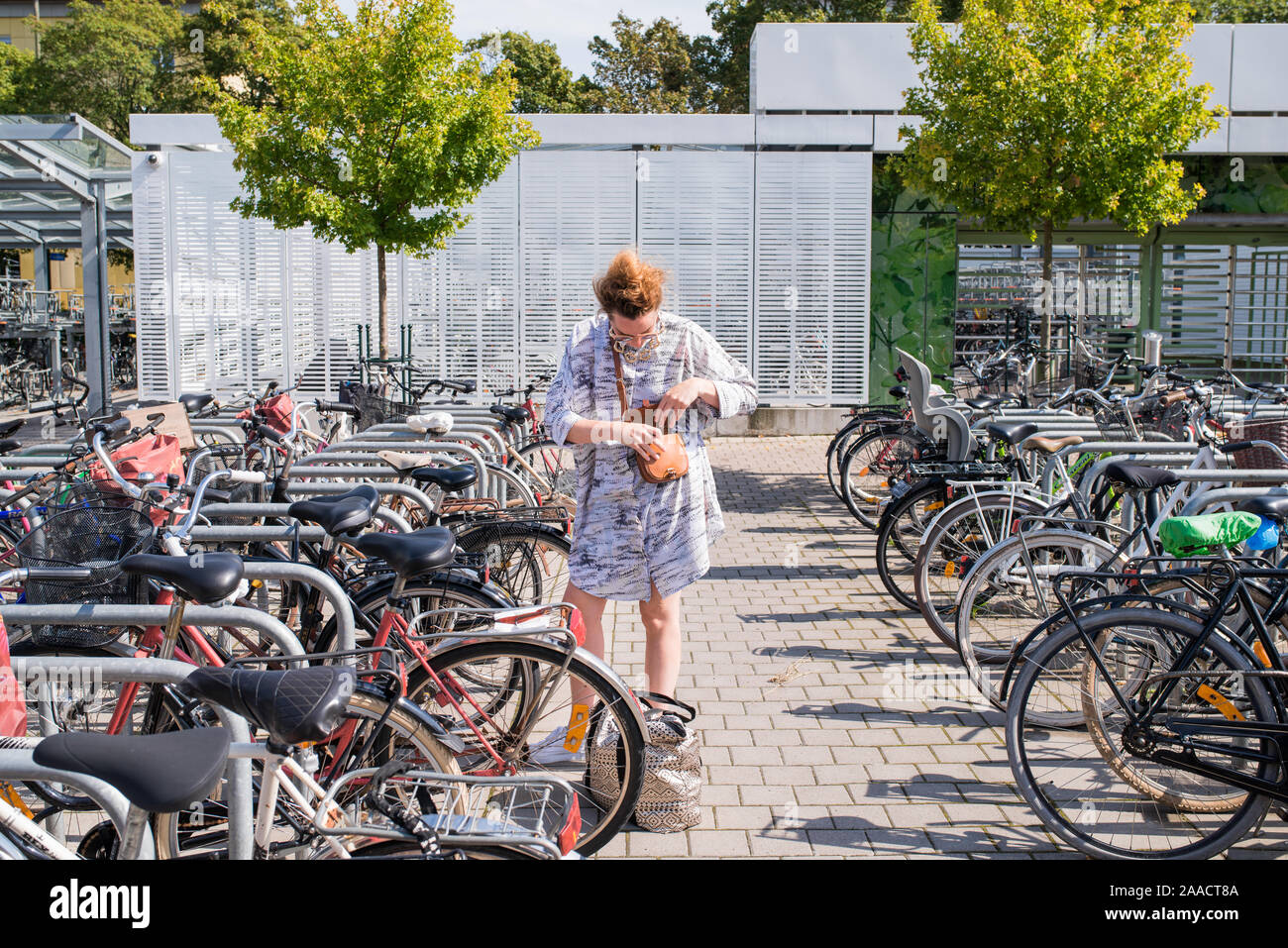 Hip Frau ihr Fahrrad Entriegelung von fahrradständer im Sommer Stockfoto
