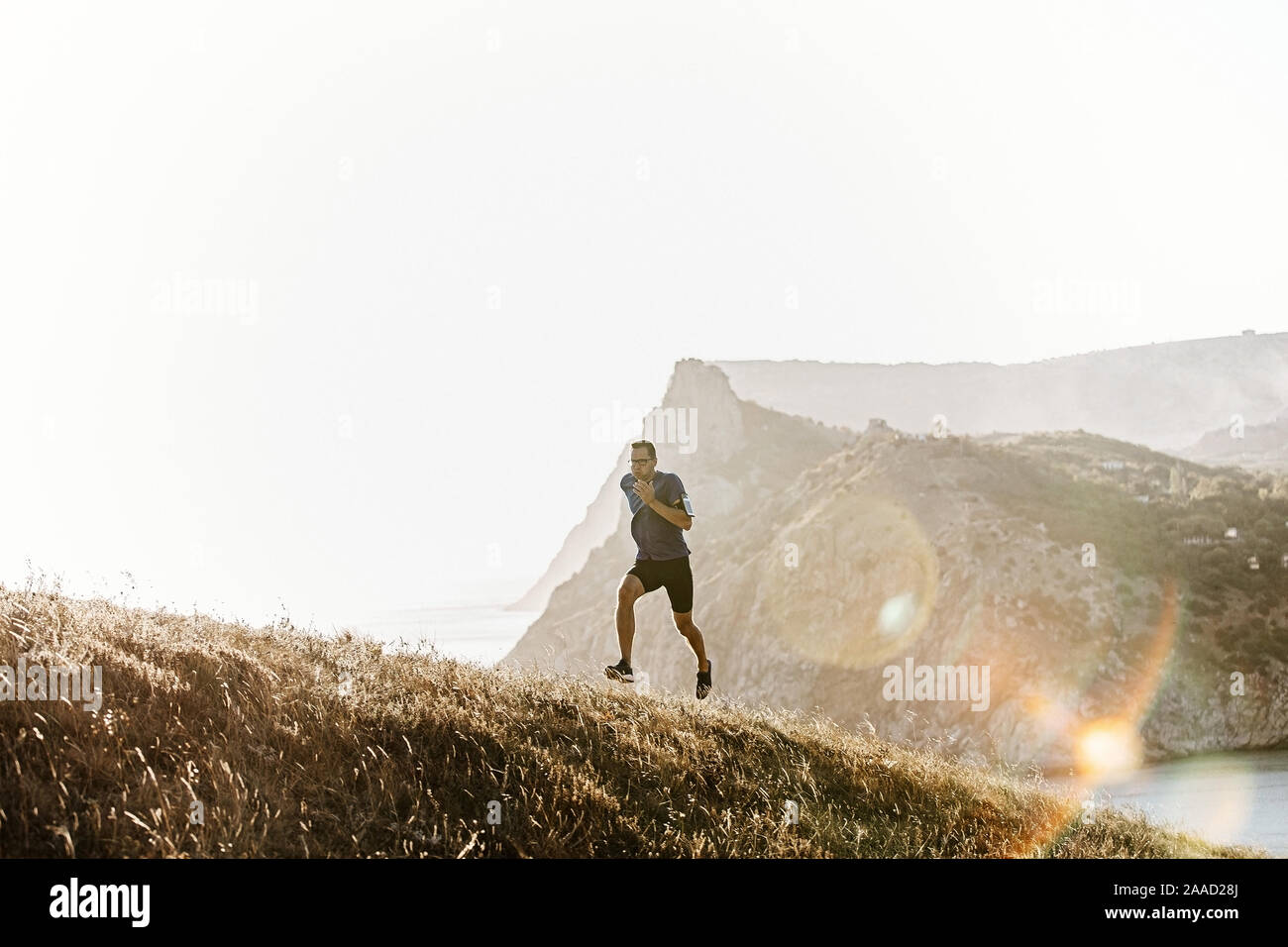 Man bergauf laufen Runner mit Brille im Sonnenuntergang, armband Inhaber Phone Case Stockfoto