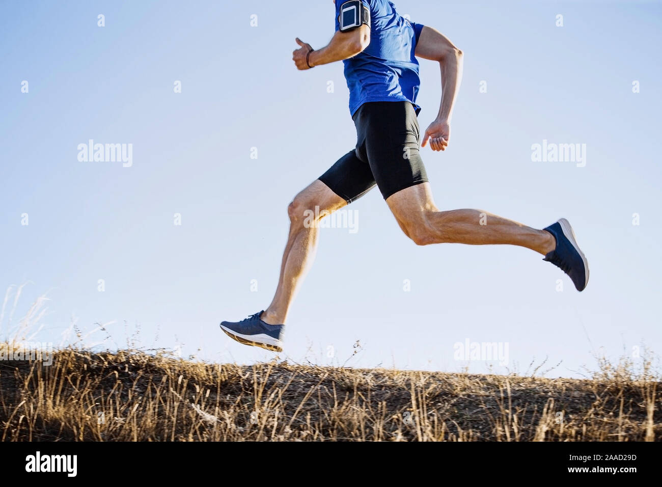 Männliche Läufer mit Mountain Trail auf blauen Himmel Hintergrund Stockfoto