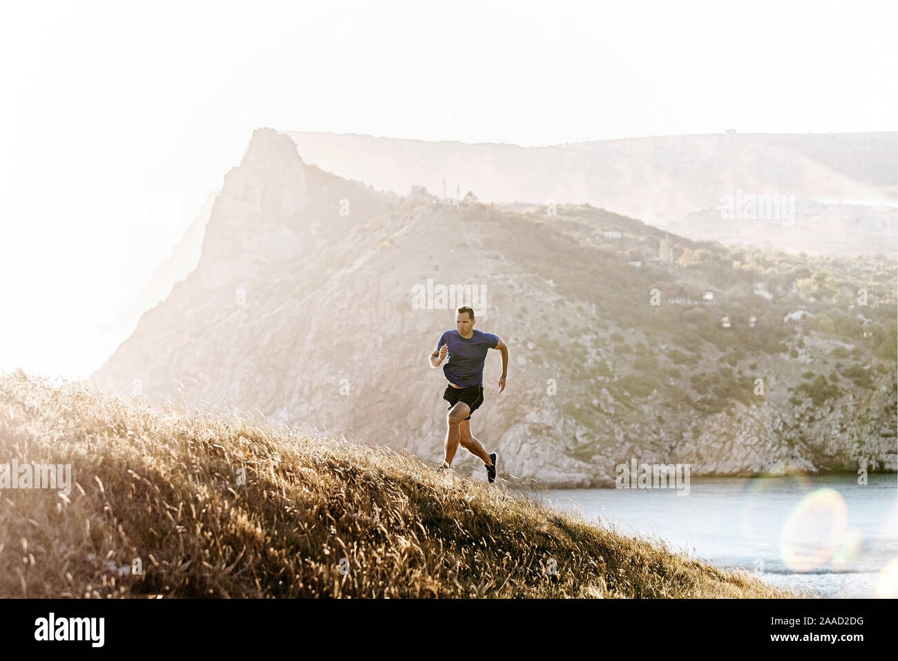Dynamische läuft bergauf männliche Läufer im Abendlicht, Berge im Meer Stockfoto