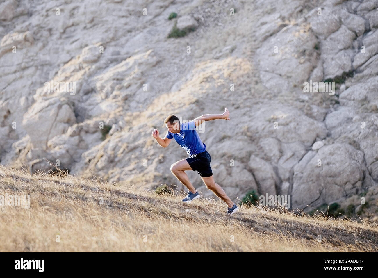 Sportliche Mann bergauf laufen auf Hintergrund Stone Mountain Textur Stockfoto
