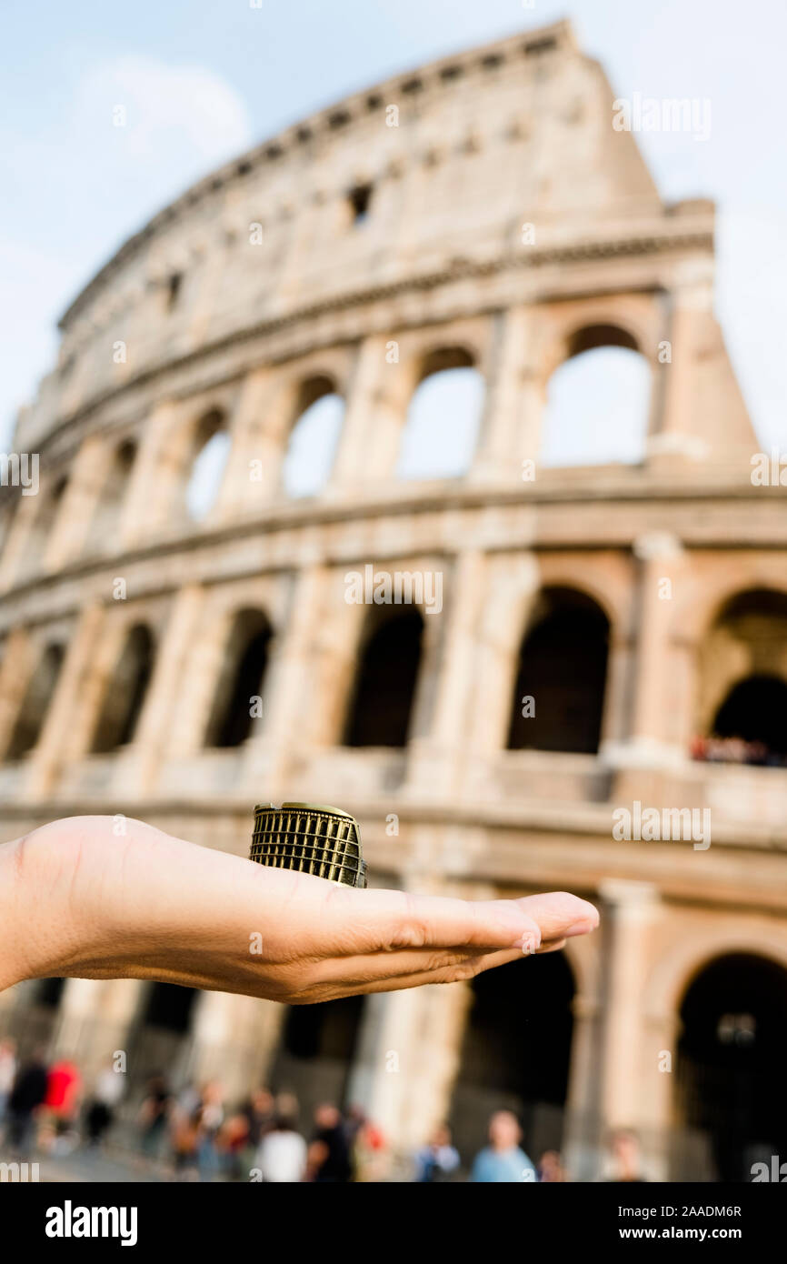 Nahaufnahme der Hand eines kaukasischen Mann hält eine Miniatur des Flavischen Amphitheater oder das Kolosseum in Rom, Italien, vor dem Wahrzeichen Stockfoto