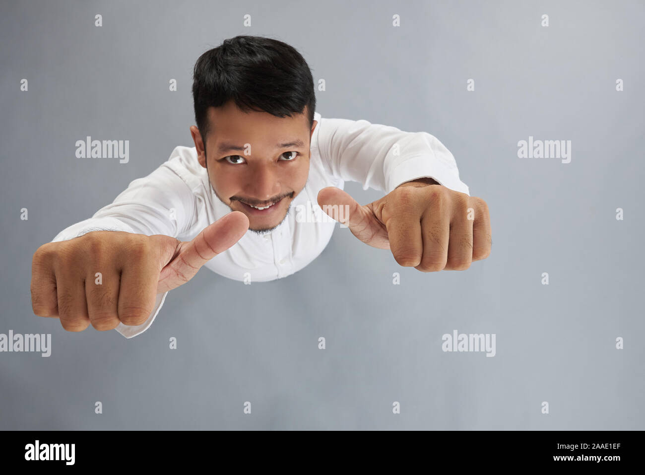 Junge asiatischer Mann zeigen Daumen oben Draufsicht auf Grau studio Hintergrund Stockfoto