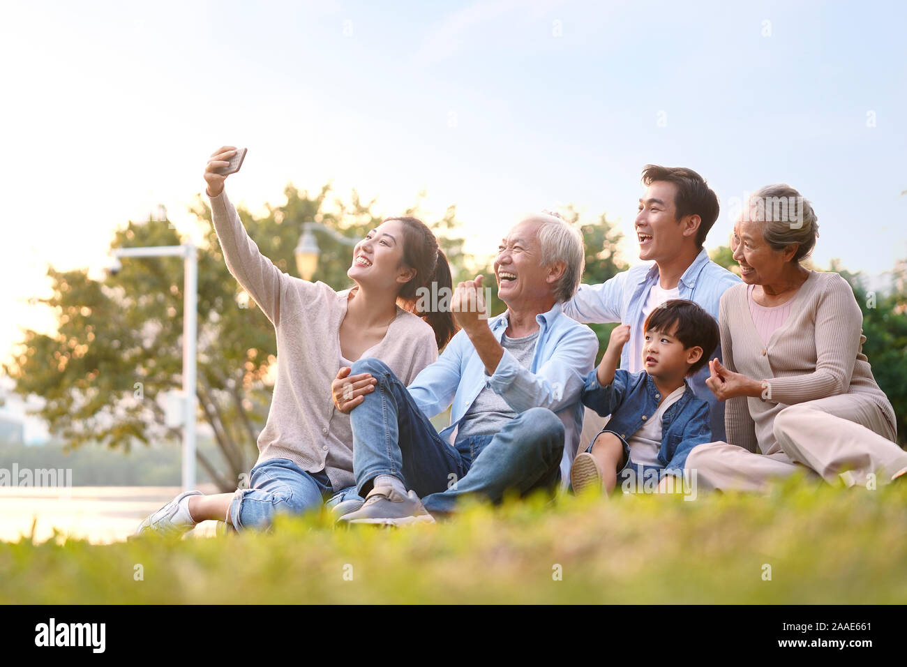 Drei generation gerne asiatische Familie sitzt auf Gras, eine selfie mit Handy draußen im Park Stockfoto